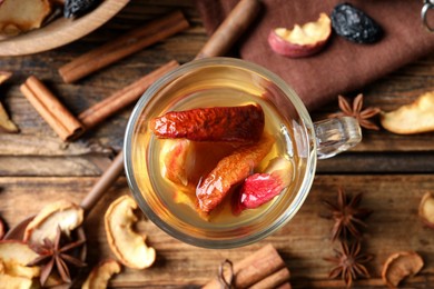 Photo of Delicious compote with dried apple slices in glass cup on wooden table, flat lay