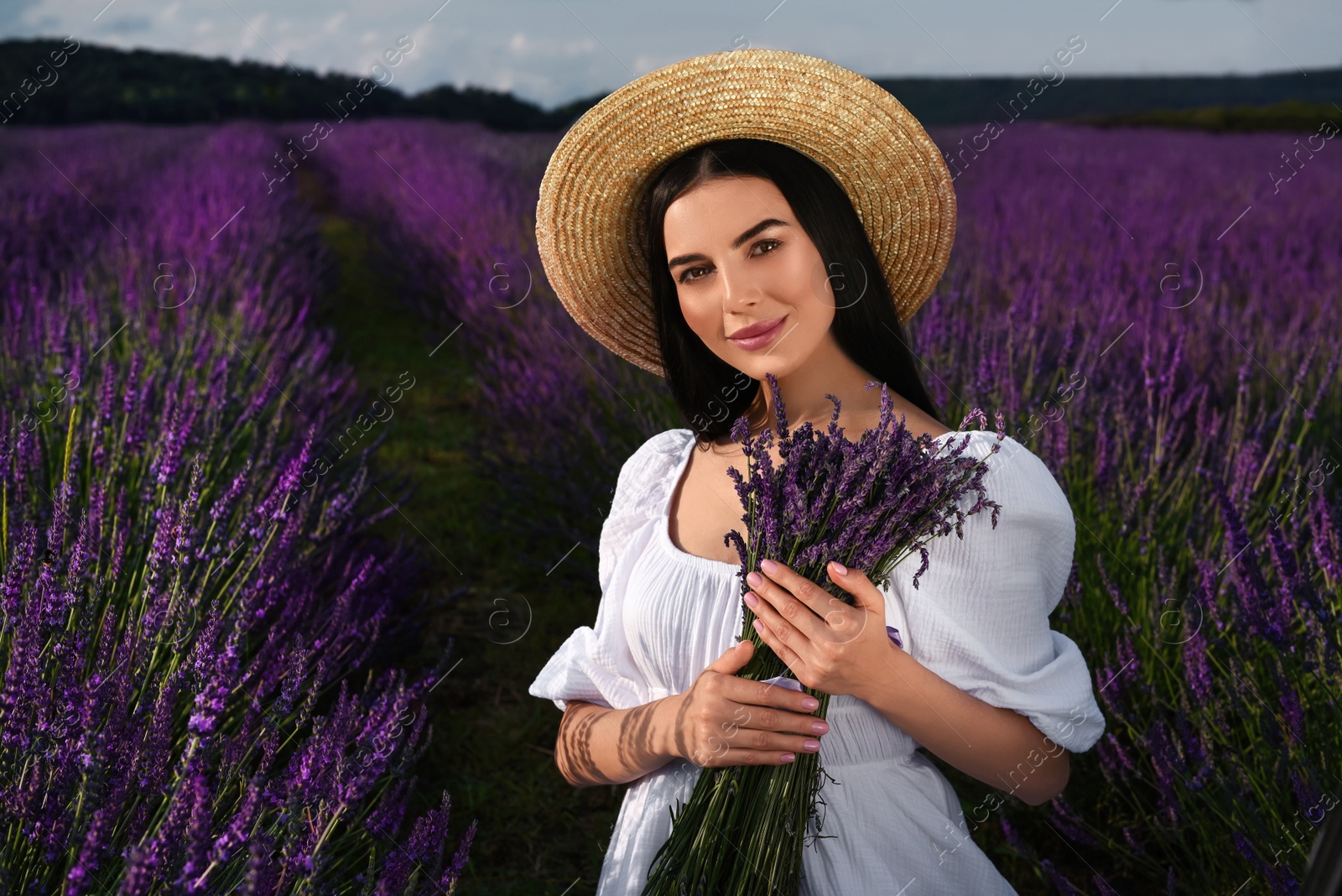 Photo of Beautiful young woman with bouquet in lavender field