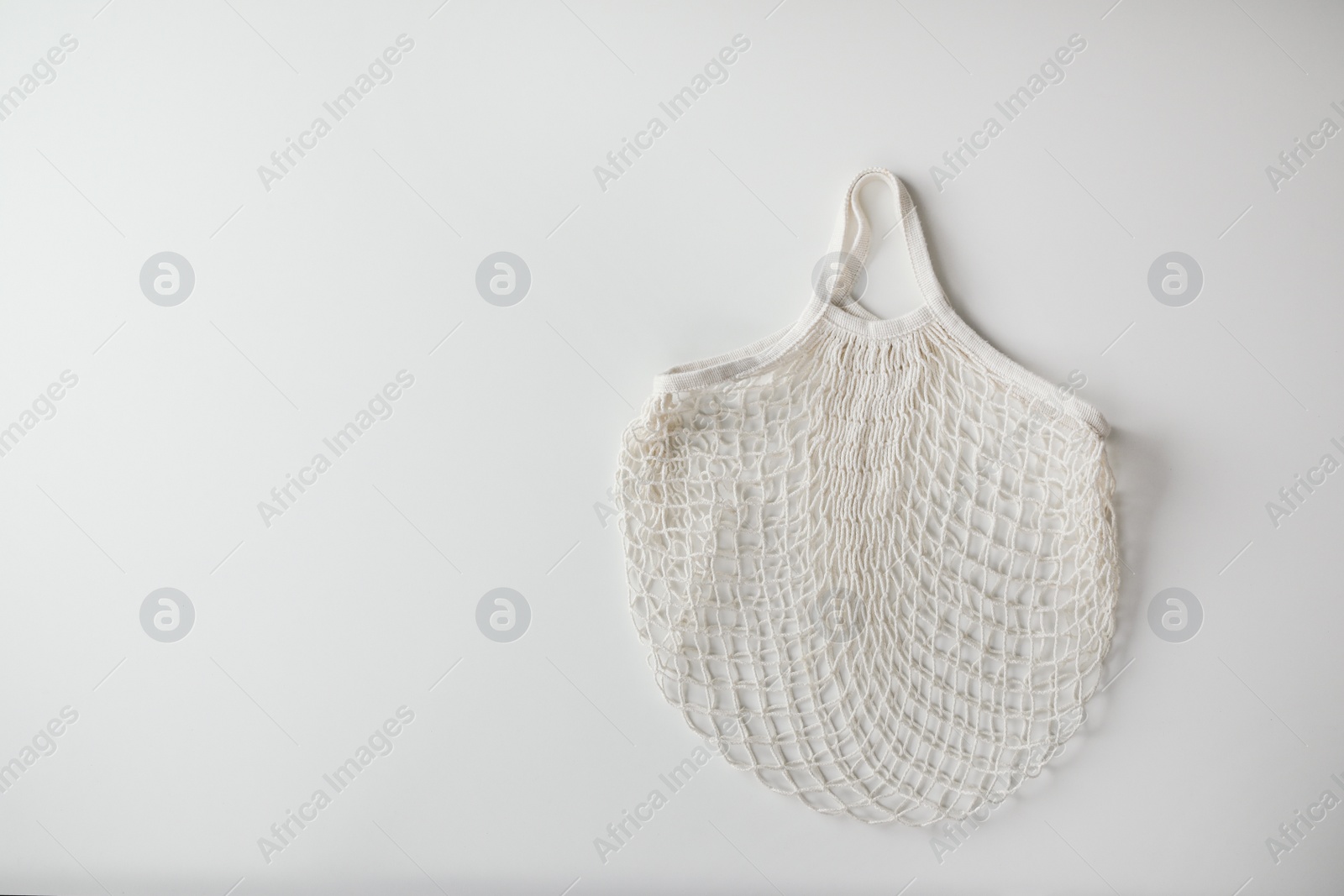 Photo of Empty net bag on white background, top view. Space for text