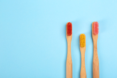 Photo of Toothbrushes made of bamboo on light blue background, flat lay. Space for text