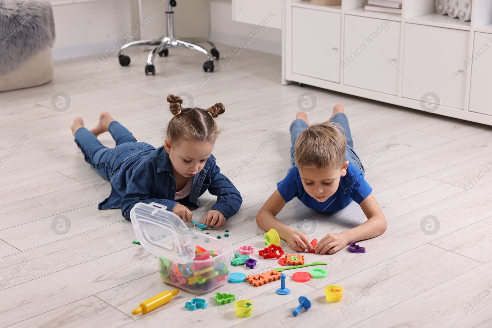 Photo of Cute little children playing on warm floor at home. Heating system