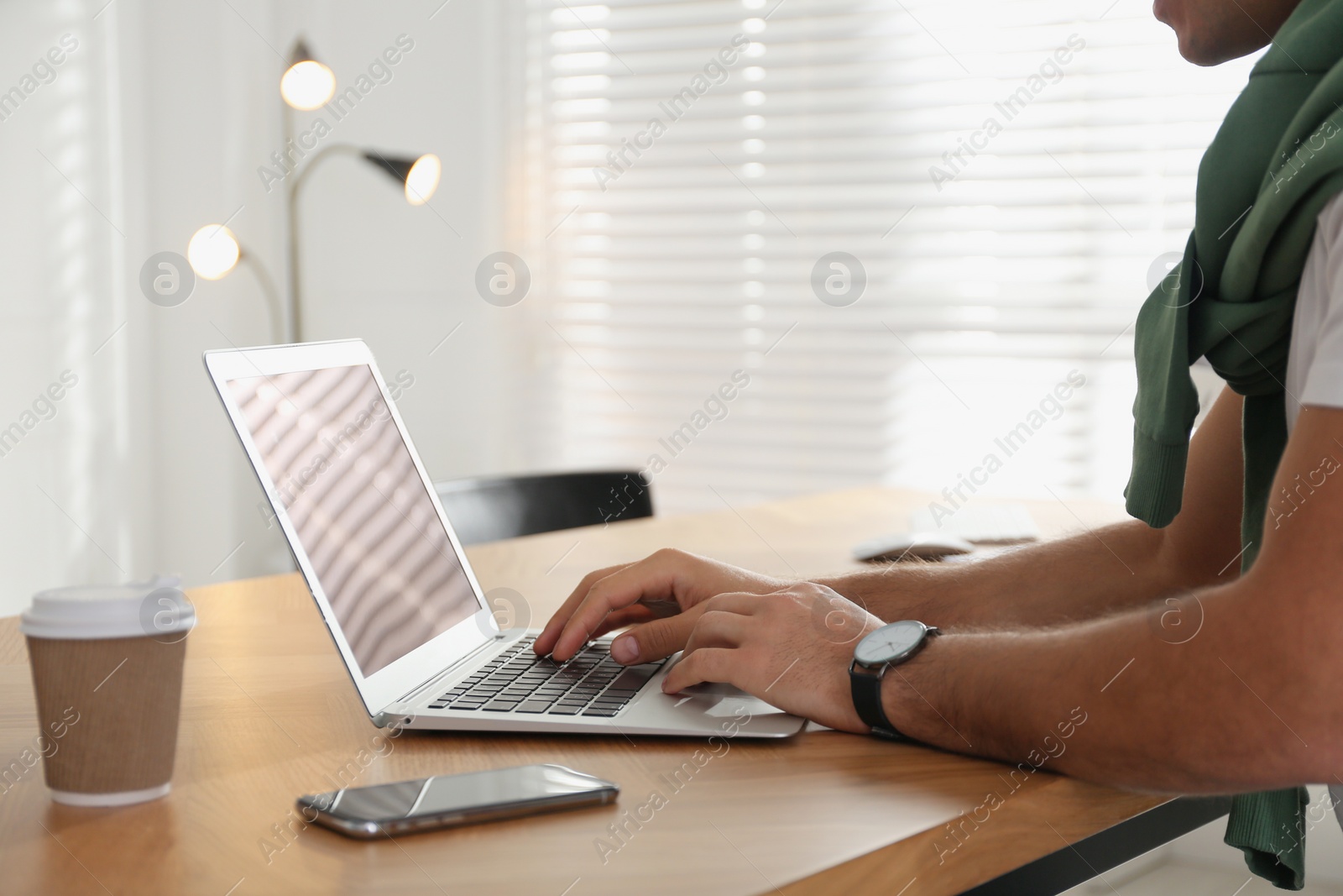 Photo of Freelancer working on laptop at table indoors, closeup