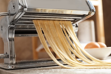 Photo of Pasta maker with dough on kitchen table