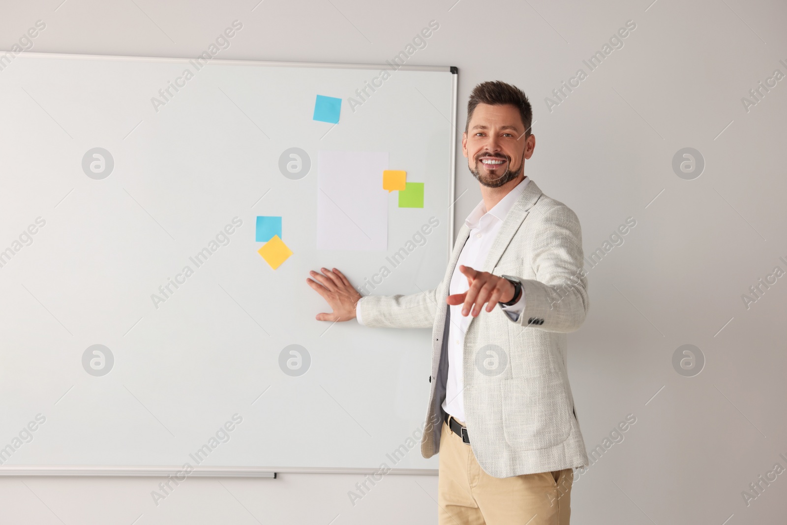 Photo of Happy teacher explaining something at whiteboard in classroom. Space for text