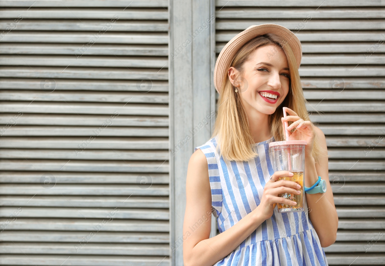 Photo of Young woman with cup of tasty lemonade near wooden wall