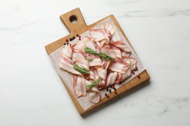 Slices of raw bacon and spices on white marble table, top view