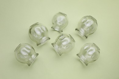 Photo of Glass cups on light olive background, flat lay. Cupping therapy