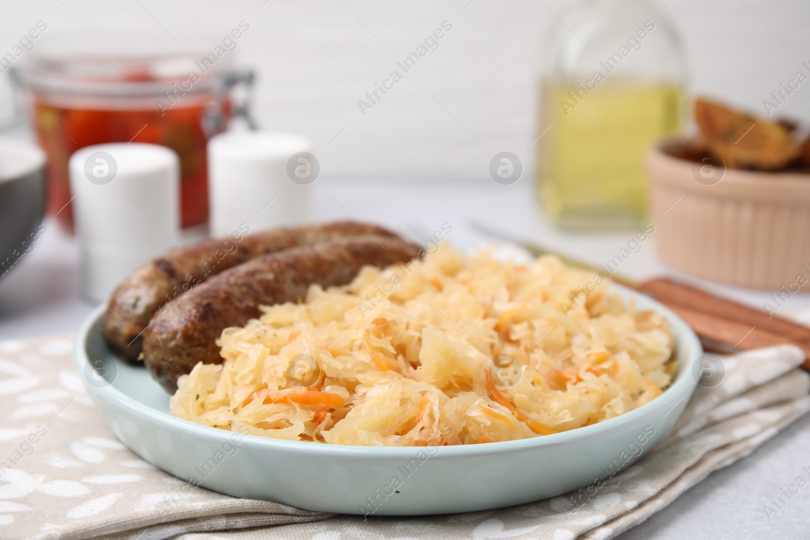 Photo of Plate with sauerkraut and sausages on table