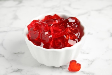 Photo of Sweet heart shaped jelly candies on white marble table, closeup