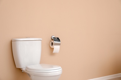 Photo of Holder with toilet paper roll on wall in bathroom. Space for text