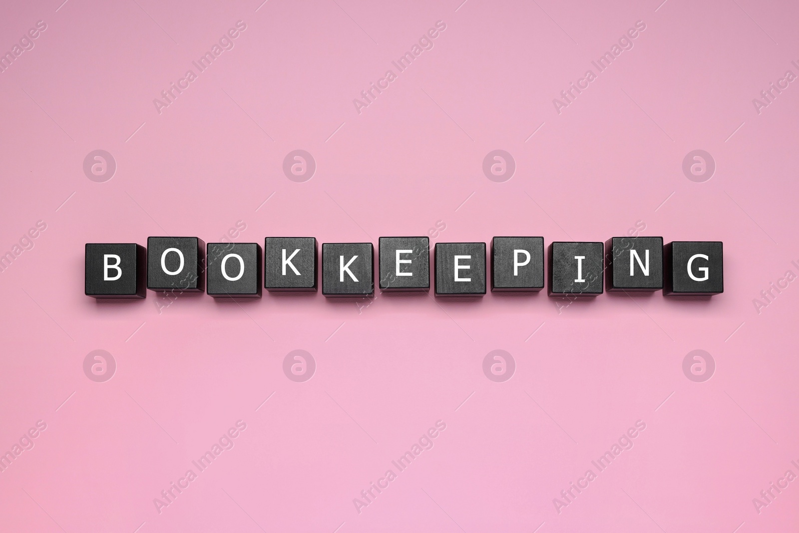 Photo of Word Bookkeeping made with black cubes on pink background, top view