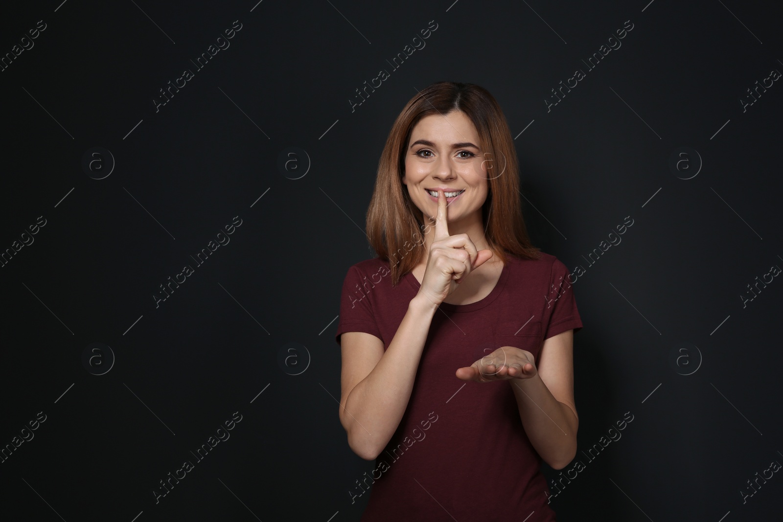 Photo of Woman showing HUSH gesture in sign language on black background, space for text