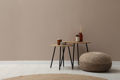 Photo of Knitted pouf and decor elements near beige wall indoors. Space for text
