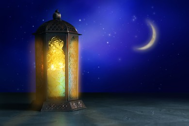 Image of Beautiful decorative Arabic lantern on table at night, space for text. Fanous as Ramadan symbol