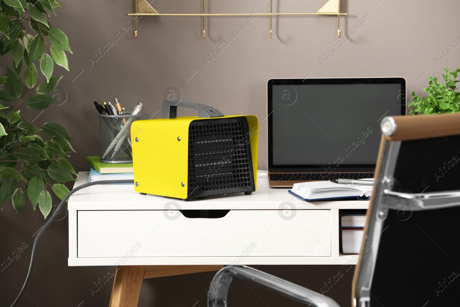 Photo of Modern electric fan heater near laptop and notebooks on white table in office