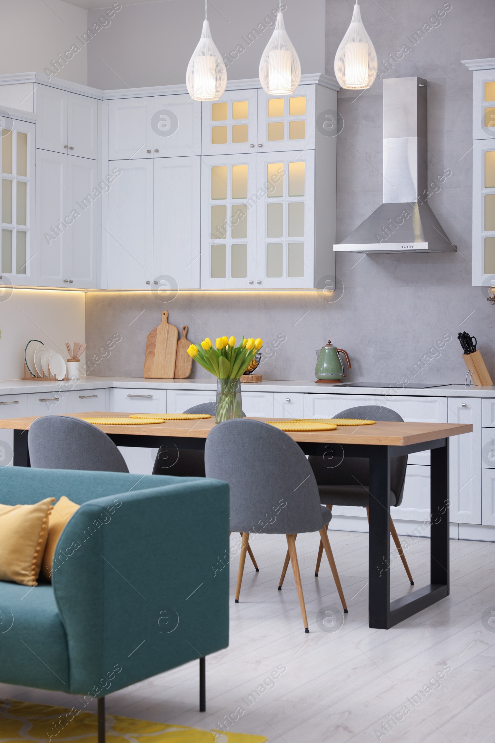 Photo of Spring atmosphere. Stylish kitchen interior with comfortable furniture and bouquet of beautiful yellow tulips