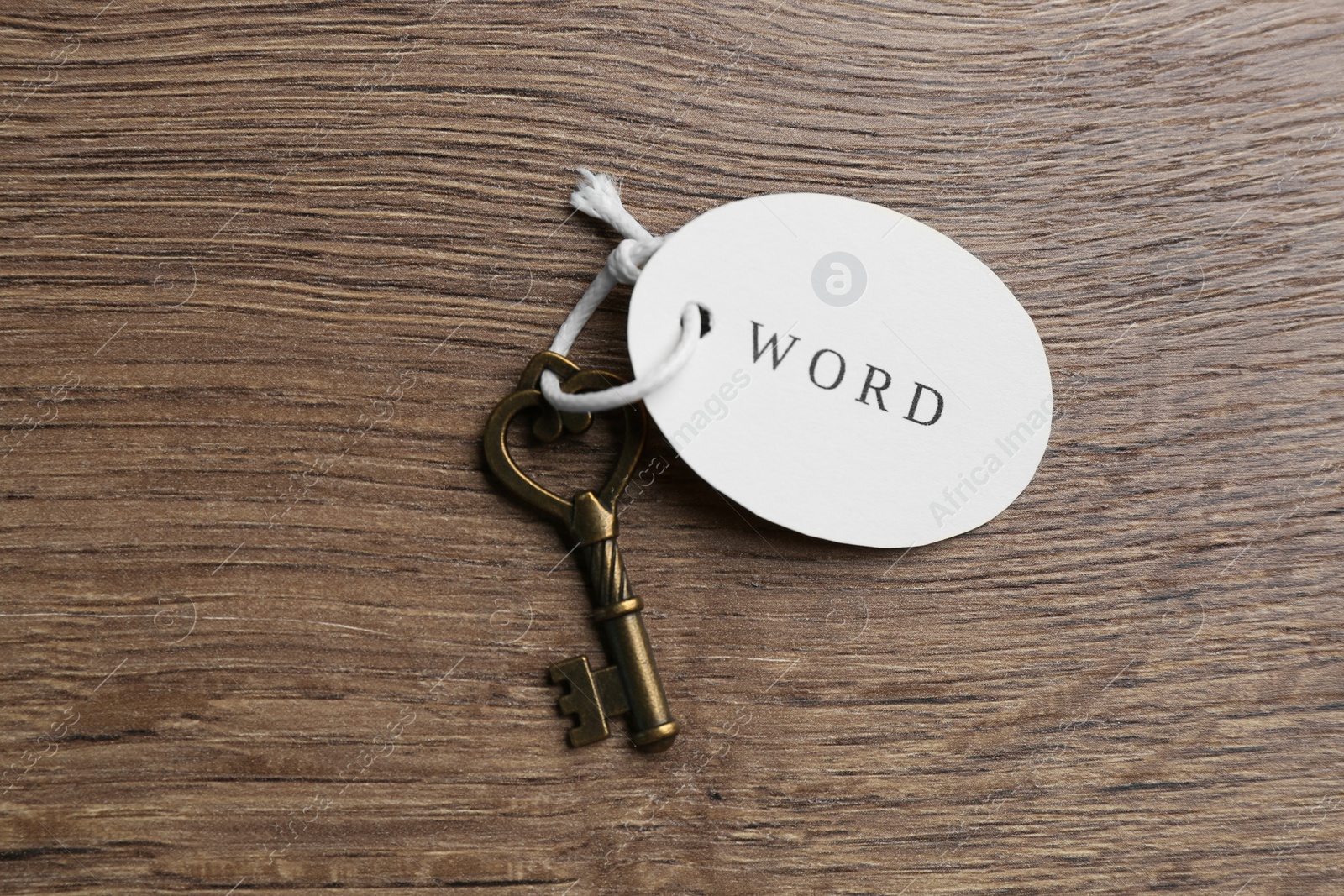 Photo of Vintage key with tag on wooden table, top view. Keyword concept