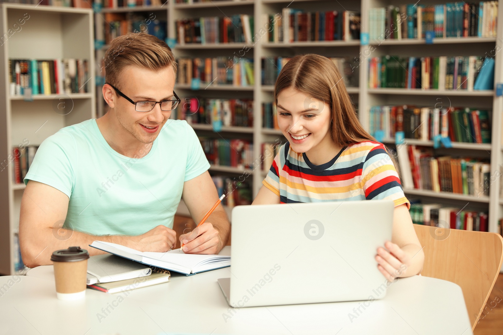 Photo of Young people discussing group project at table in library