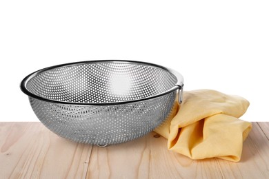 Metal colander and napkin on wooden table against white background