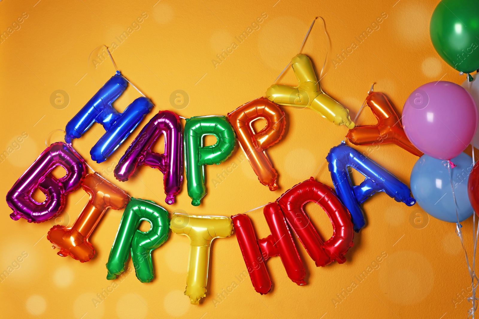 Photo of Phrase HAPPY BIRTHDAY made of colorful balloon letters on orange background