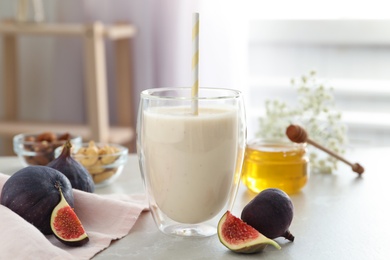 Photo of Delicious fig smoothie in glass on light table