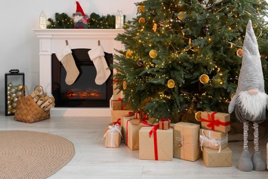 Many different gift boxes under Christmas tree and festive decor in living room