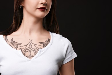 Woman with cool tattoos on black background, closeup. Space for text