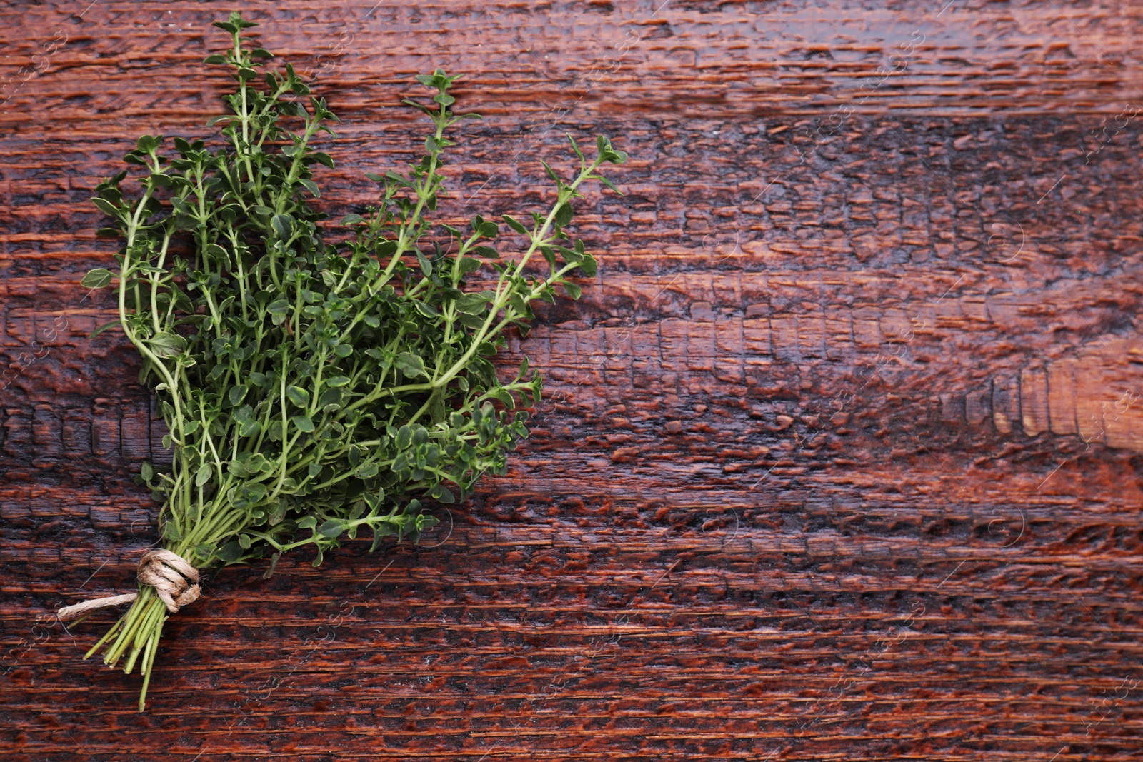 Photo of Bunch of aromatic thyme on wooden table, top view. Space for text