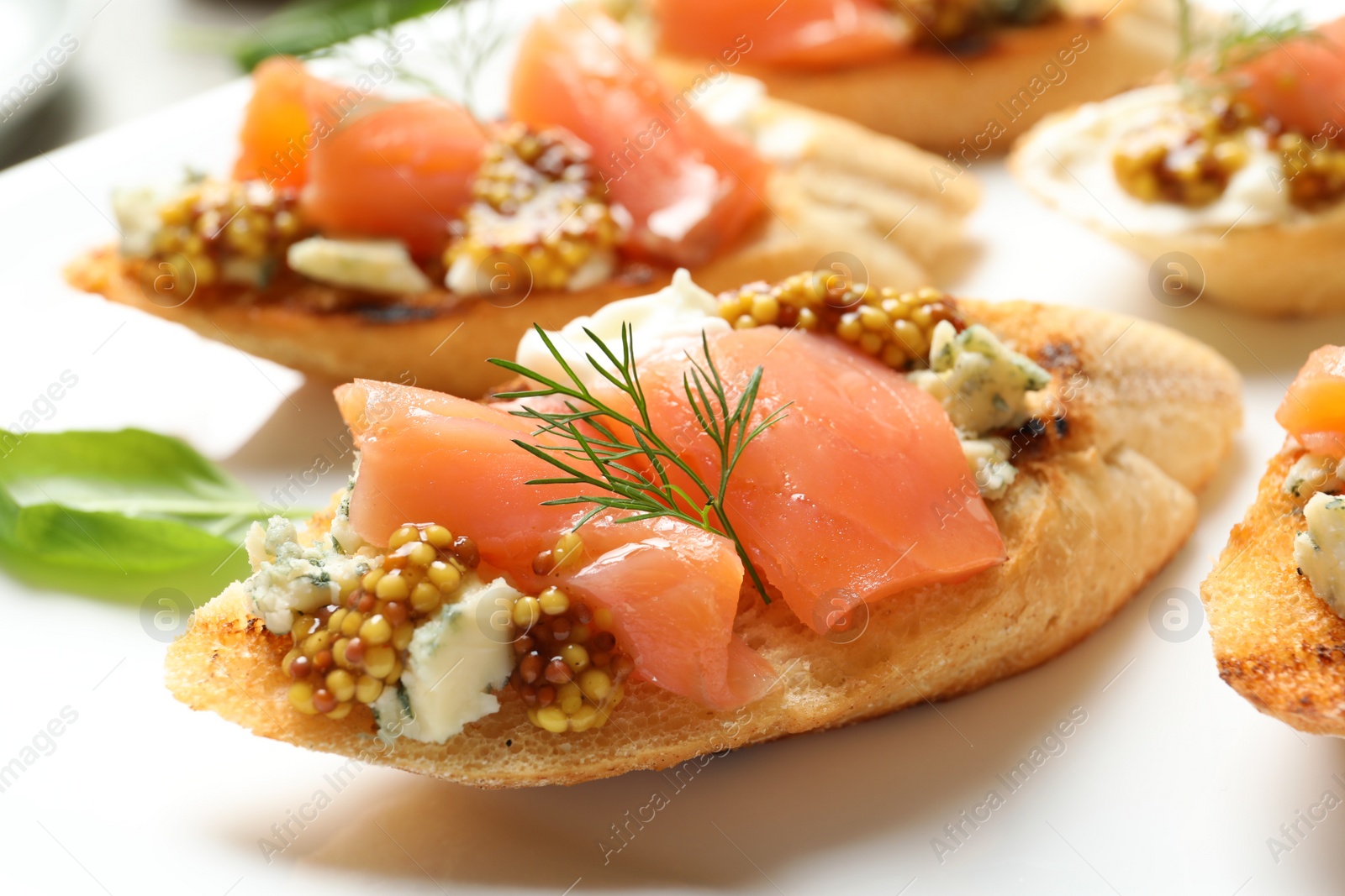 Photo of Tasty bruschettas with salmon and blue cheese on plate, closeup