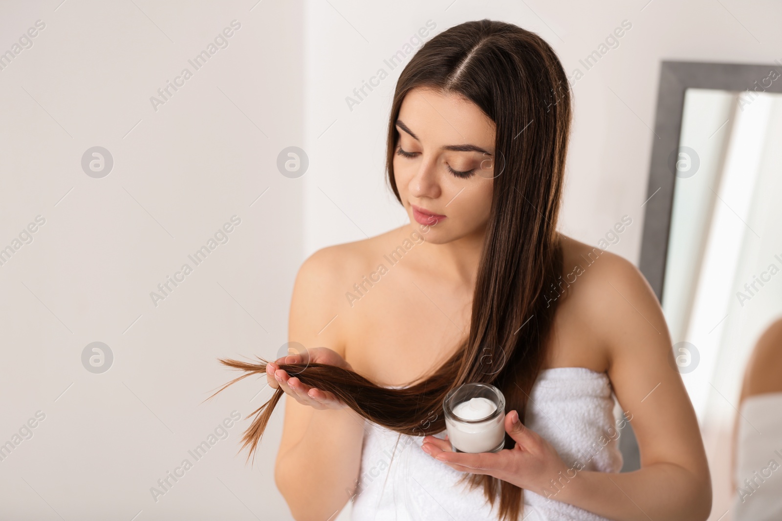 Photo of Woman with glass bowl of hair mask indoors. Space for text