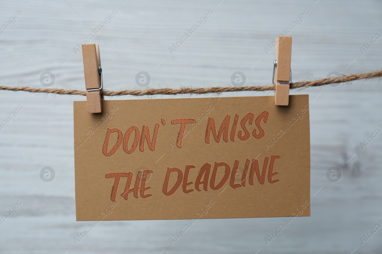 Image of Note with reminder Don't Miss The Deadline hanging on twine against light background