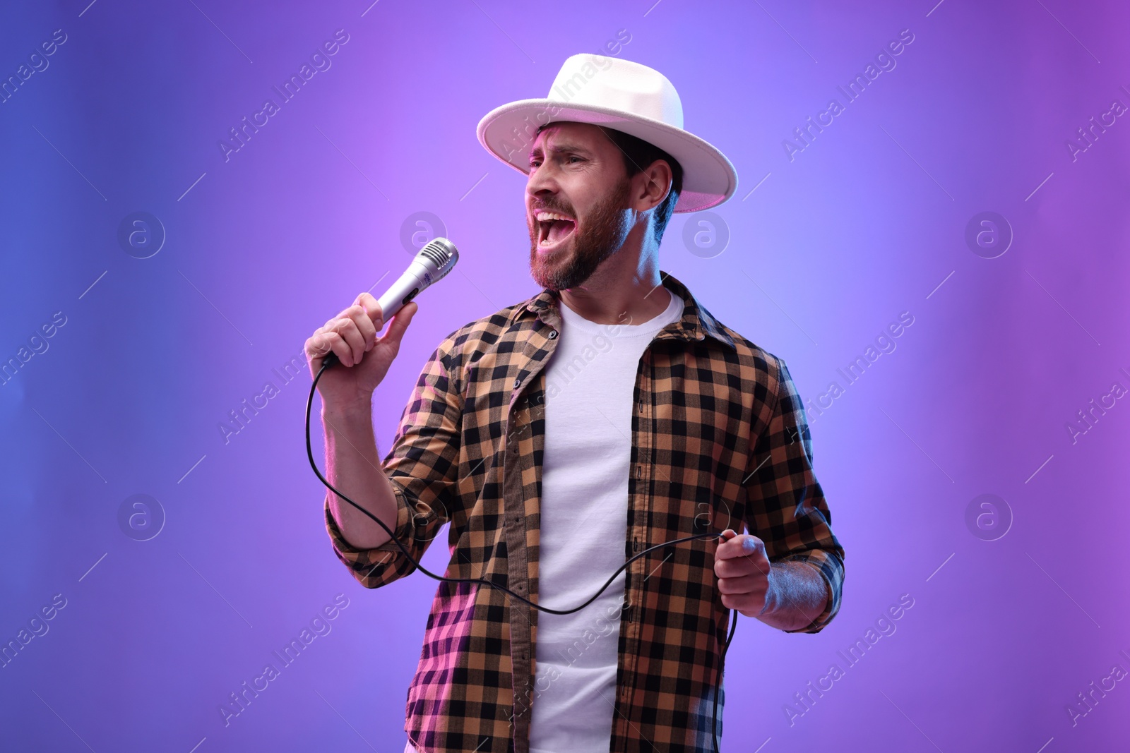 Photo of Emotional man with microphone singing in neon lights