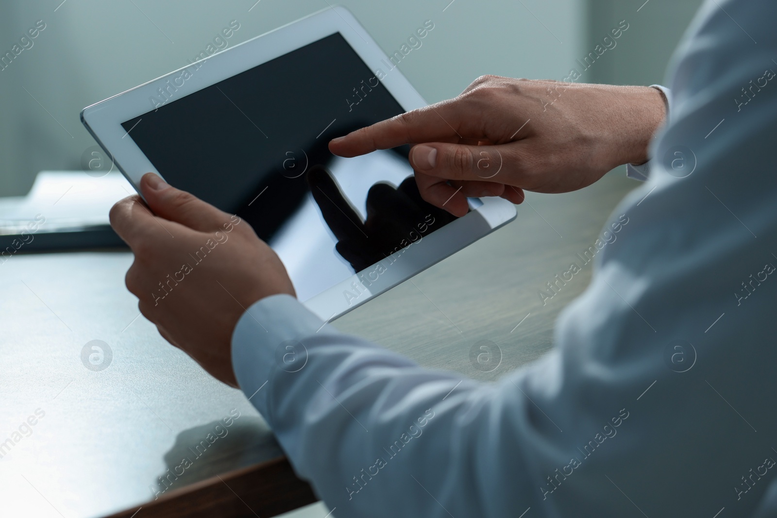 Photo of Man using tablet at wooden table, closeup