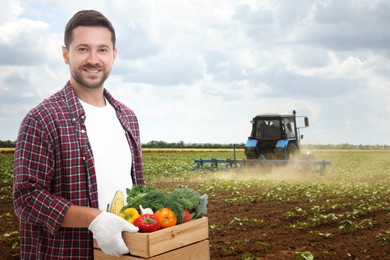 Image of Harvesting season. Farmer holding wooden crate with crop in field