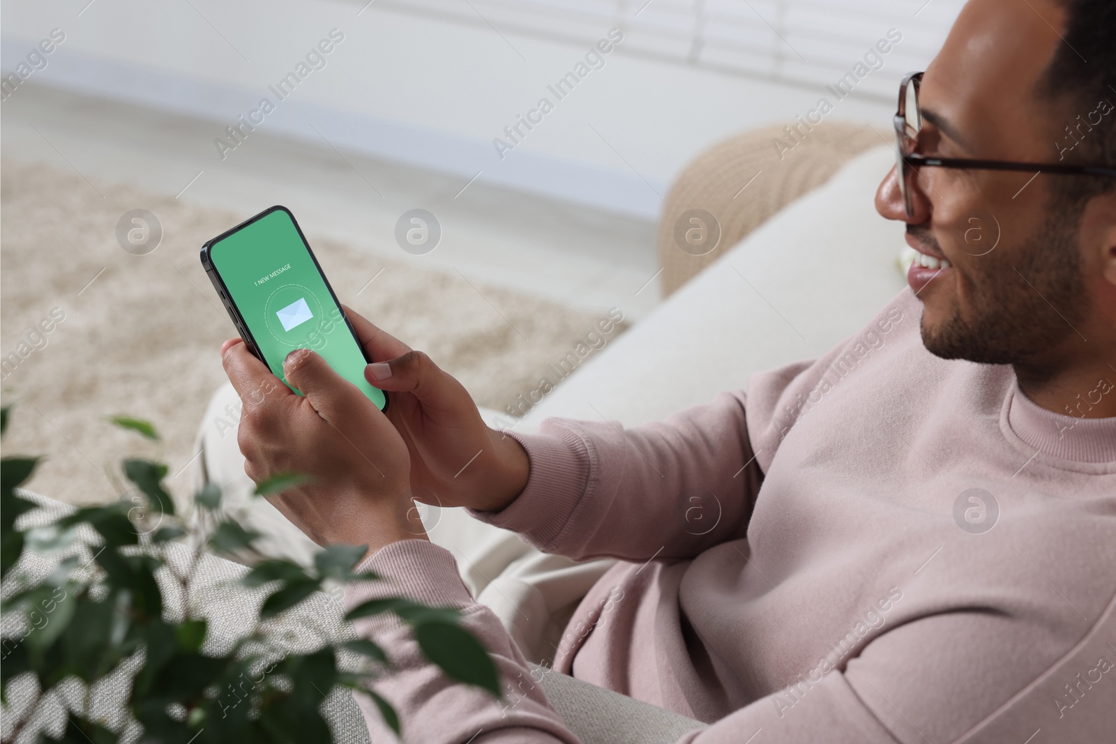 Image of Man checking new message on mobile phone indoors