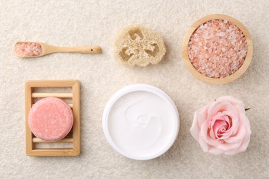 Flat lay composition with moisturizing cream in open jar and other body care products on light textured table