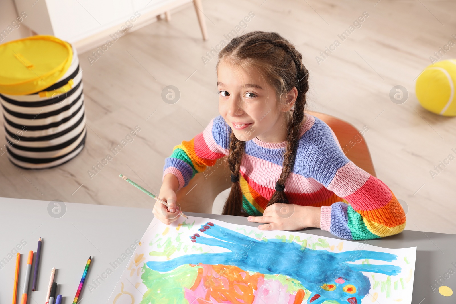 Photo of Little girl drawing picture at table indoors