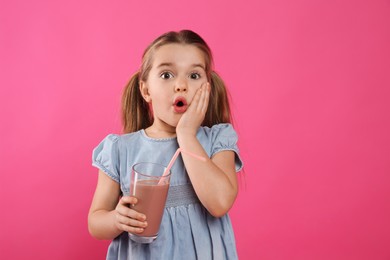 Surprised little child with glass of tasty chocolate milk on pink background, space for text