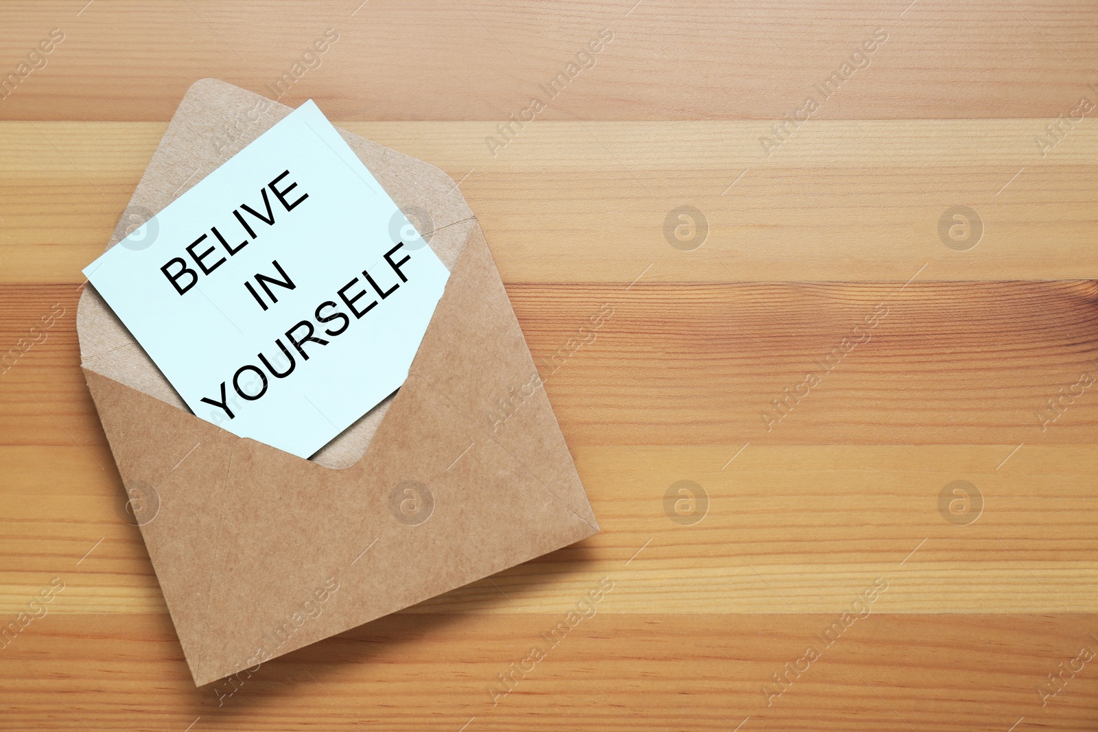 Photo of Envelope and phrase Believe In Yourself on wooden table, top view with space for text. Motivational quote