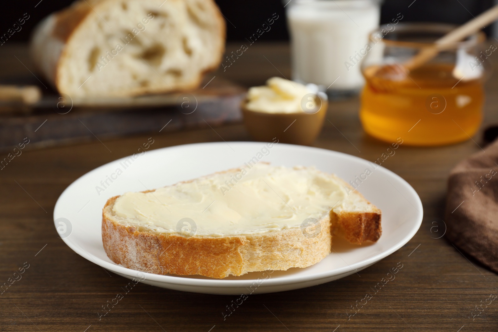 Photo of Sandwich with butter near honey on wooden table, closeup