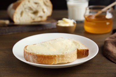 Photo of Sandwich with butter near honey on wooden table, closeup
