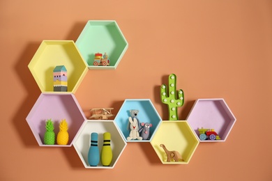 Photo of Hexagon shaped shelves with toys on orange wall. Interior design
