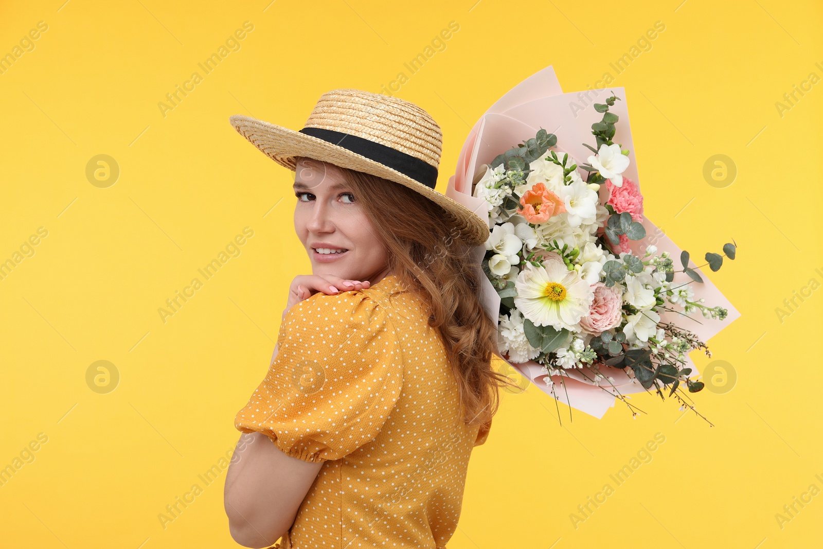Photo of Beautiful woman in straw hat with bouquet of flowers on yellow background