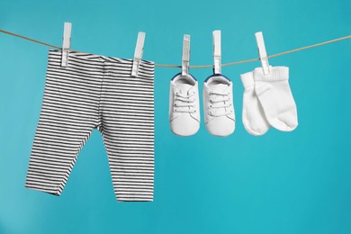 Photo of Striped baby pants, shoes and socks drying on washing line against turquoise background