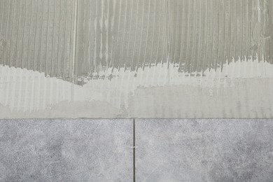 Photo of Adhesive mix and ceramic tiles on wall, closeup