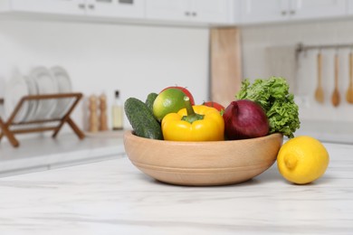 Bowl with fresh ripe vegetables and fruits on table in kitchen