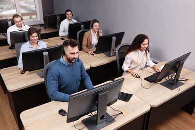 Photo of Call center operators with headsets working in modern office, above view