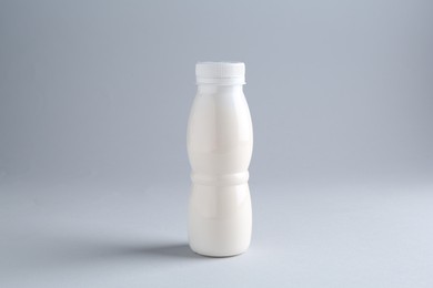 Photo of Tasty yogurt in bottle on light grey background
