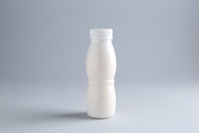 Tasty yogurt in bottle on light grey background