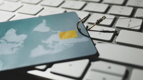 Photo of Hook with credit card on computer keyboard, closeup. Cyber crime concept